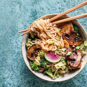Overhead view of Maple Curry Garlic Ramen Noodle Bowl with wooden chopsticks on a light blue background