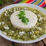 Salsa Verde Dip with Queso Fresco on a white plate with Mexican striped napkin in the background