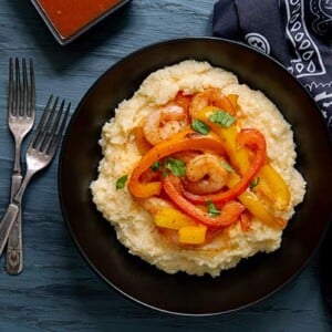 Overhead view of South-of-the-Border Shrimp and Grits in a black bowl on a gray-blue background