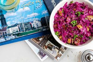 caraway spiced red cabbage in a white bowl with German postcards underneath