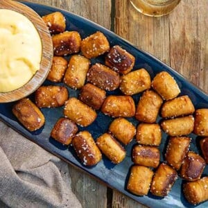 Overhead view of Classic Pretzels with Beer Cheese on a dark blue oval platter on wood background