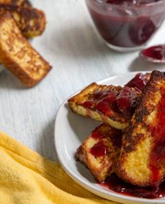 Overhead view of white plates with French Toast Sticks with Cherry Sauce and a yellow cloth napkin on the side