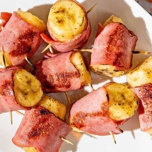 Overhead view of Bananas in Blankets on a white plate on top of a colorful floral tablecloth