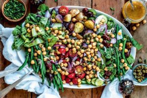 Overhead view of Chickpea Salad Nicoise on a white oval platter on a wooden table