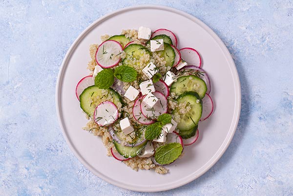 Overhead view of Cucumber Quinoa Salad on a white plate on a light blue background