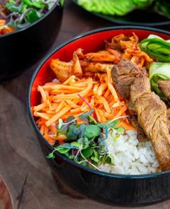 Closeup of Easy Beef Bulgogi Bowls in black and red bowls on a dark wooden serving board