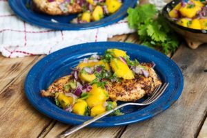 Grilled Chicken & Mango Salsa on a blue plate on a wooden table