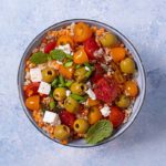 Overhead view of Lentil and Tomato Salad in a gray bowl on a light blue background