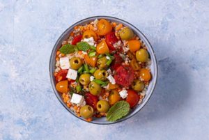 Overhead view of Lentil and Tomato Salad in a gray bowl on a light blue background
