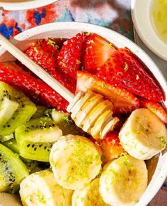 Overhead view of Lime-Kissed Chunky Tropical Fruit Salad in a white bowl on a colorful floral tablecloth