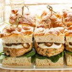 Mediterranean Style Salmon Sliders on a white platter on a beige tablecloth