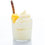 Pineapple Whip in a glass topped with pineapple chunks with a wooden spoon isolated on a white background