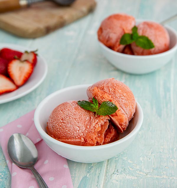 Strawberry and Mango Sorbet in white bowls on a white table with pink napkin