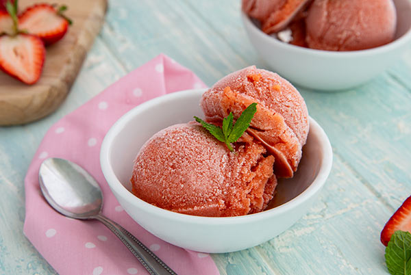 Strawberry and Mango Sorbet in a white bowl on a white table with pink napkin