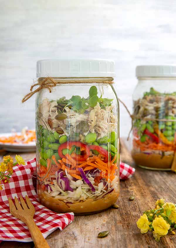 Thai Chicken Salad-in-a-Jar on a wood table with red and white checkered napkin underneath