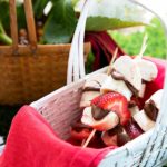 Bagel Skewers with bagen pieces and strawberries in a picnic basket with red cloth napkin inside