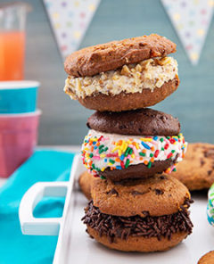 Stack of Easy Ice Cream Sandwiches on a white tray on a teal placemat with bright cups and punch and a party banner in the background