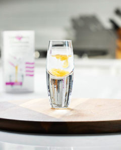 LivOn Labs Glutathione liposomal supplement in a shot glass of water on a wood cutting board in a modern white kitchen
