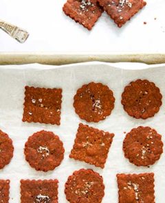 Overhead view of Cassava Beet Powder Crackers on a parchment paper lined baking tray on a white marble table