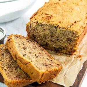 Closeup of My Favorite Banana Bread on a piece of parchment paper on top of a wooden board on a white marble countertop