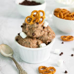 Not-So-Rocky Road Ice Cream in a white ramekin topped with pretzels with a bowl of pretzels and chocolate chips in the background on a white marble counter