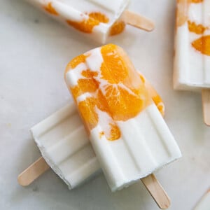 Overhead view of white and orange Sunshine Popsicles on a white marble countertop