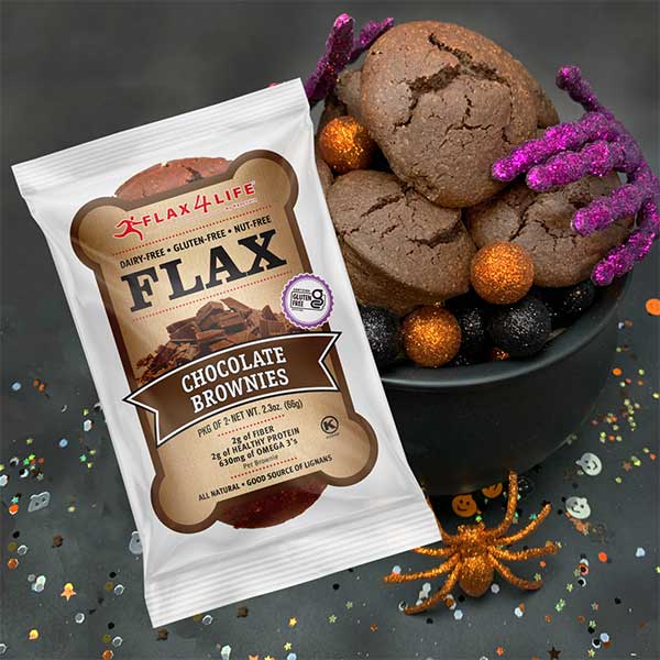 Flax4Life Brownies with sparkly purple skeleton hands and orange spider with Halloween confetti on a black background