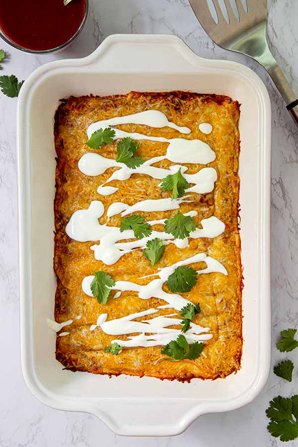 Overhead view of Lazy Enchiladas in a white rectangular baking dish on a white marble table