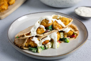 Chicken Tender Pitas on a white plate with tzatziki sauce drizzled on top