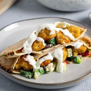 Chicken Tender Pitas on a white plate with tzatziki sauce drizzled on top