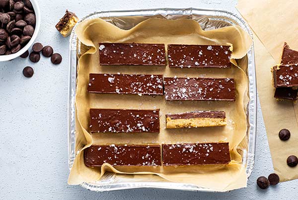 Overhead view of Chocolate Bars sprinkled with sea salt in an aluminum baking pan lined with parchment paper
