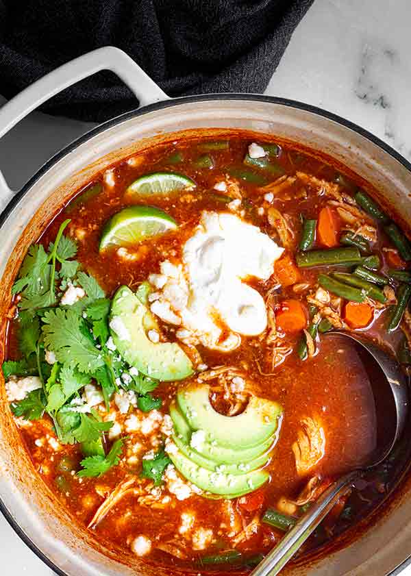 Closeup overhead view of Mexican Soup in a pot with avocado and cilantro on top