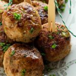 Close-up of Chinese 5-Spice Meatballs with picks in them and sprinkled with fresh herbs