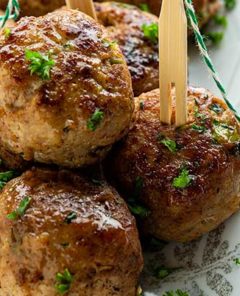 Close-up of Chinese 5-Spice Meatballs with picks in them and sprinkled with fresh herbs