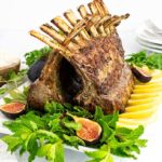 Mint and Herb Rack of Lamb on a white rectangular platter garnished with lemon slices and mint and figs