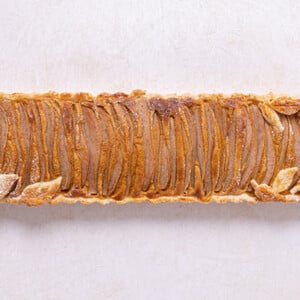 Overhead view of Pear Pumpkin Pie with leaf pie crust cutouts on an off-white background