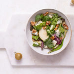 Overhead view of Pear Salad with Blue Cheese Honey Vinaigrette in a white bowl on a white marble cutting board