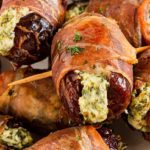 Closeup of Prosciutto-Wrapped Stuffed Dates with cheese mixture coming out of them and toothpicks through the center