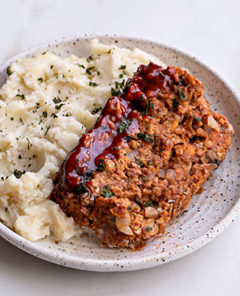 Vegan Meatloaf with mashed potatoes on a white speckled plate on a white background