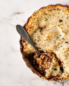 Overhead view of Vegan Shepherds Pie with a spoonful taken out on a white marble table