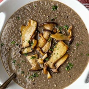 Overhead view of Wild Mushroom Bisque in a white bowl with sauteed trumpet mushrooms on top as garnish