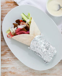 Over head view Beef Shawarma wrap on a white oval plate