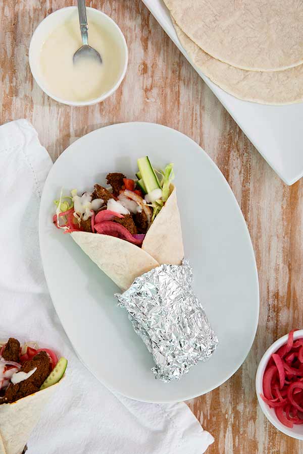 Overhead view of Beef Shawarma wrap on a white oval plate 
