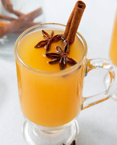 Cough-Soothing Kinderpunsch in two clear glass mugs with star anise and cinnamon sticks inside