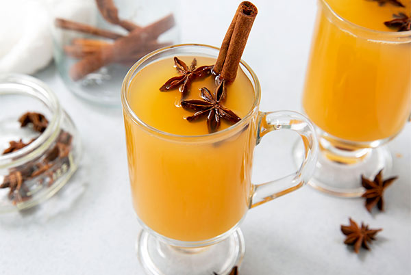 Cough-Soothing Kinderpunsch in two clear glass mugs with star anise and cinnamon sticks inside