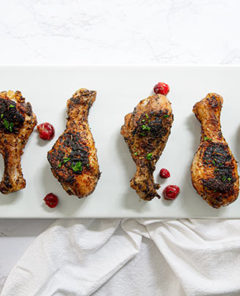 Overhead view of Cranberry Rosemary Baked Chicken Legs in a row on a white rectangular serving dish