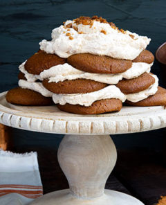 Ginger Snap Icebox Cake on a white cake stand against a dark gray background with copper cups in the background