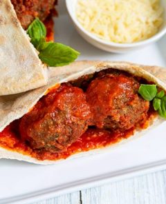 Overhead view of Plant-Based Marinara Pita Kit on a white plate with blue and white striped napkin and garnished with basil leaves