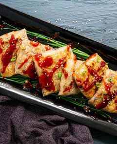 Overhead view of Turkey Rice Paper Dumplings with Cranberry Dipping Sauce on a black rectangular plate on a dark gray wood table