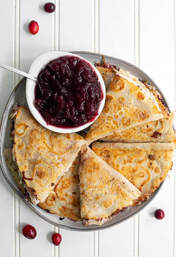 Overhead view of Turkey and Cranberry Quesadillas with a white ramekin of cranberry sauce on the side